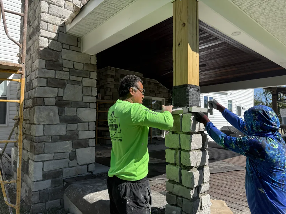 Crew members applying stone veneer to a support column