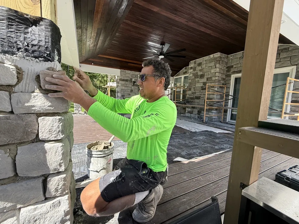 Installer setting a stone by hand on a veneered patio column