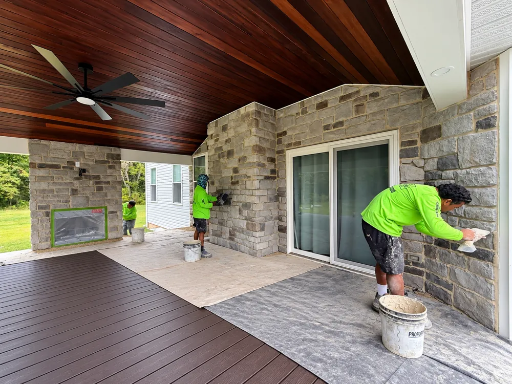 Stone veneer going up around patio doors and an outdoor fireplace